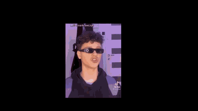 a young man with curly hair is making a funny face while wearing a black hoodie .