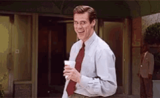 a man in a white shirt and red tie is smiling and holding a cup of coffee .