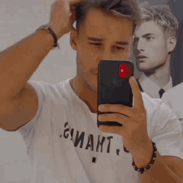 a man taking a picture of himself in front of a poster of a man