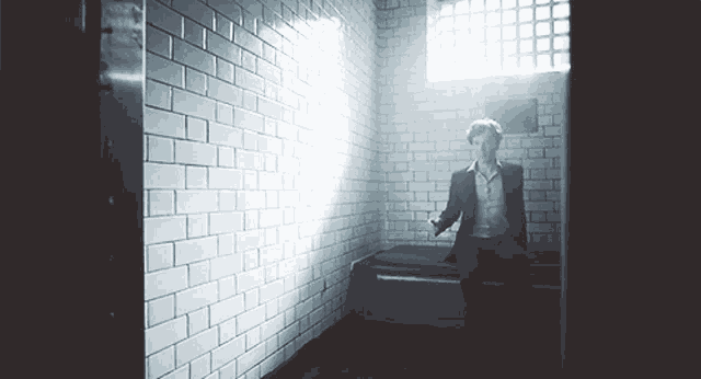 a man in a suit is standing in a dark room with a window