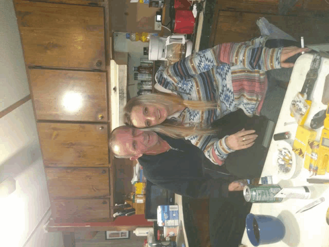 a man and a woman are posing for a picture in the kitchen