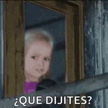 a little girl is looking out of a window and saying `` que dijites ? ''