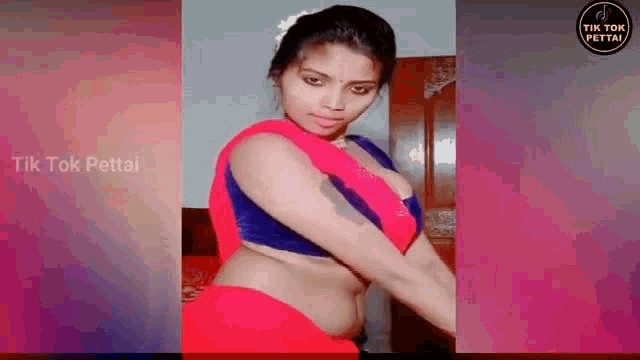 a woman in a red saree and a blue top is dancing in a room .