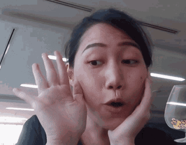 a woman with a surprised look on her face holds her hands to her face