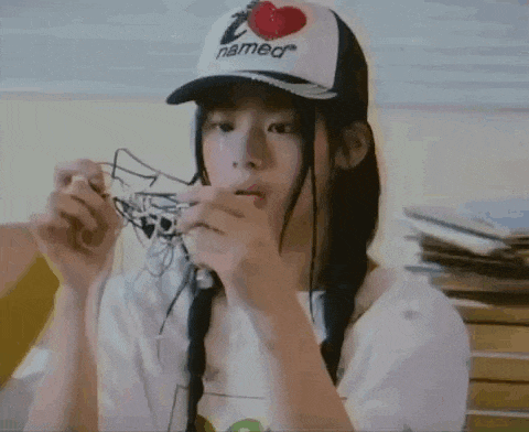 a girl wearing a hat with a heart on it is holding a pair of headphones in her hands .
