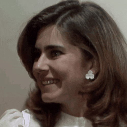 a close up of a woman 's face with a flower earring