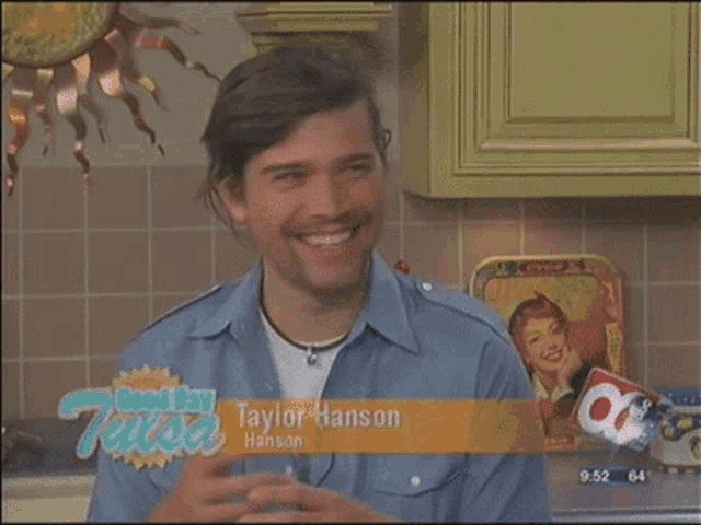 a man in a blue shirt is smiling in front of a ktl.com sign
