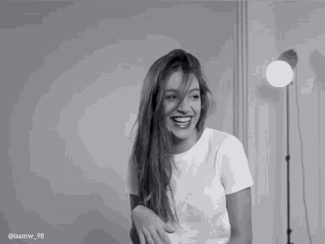 a woman in a white t-shirt is smiling in a black and white photo taken by @ isamw_98