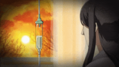 a woman is looking out a window at a sunset with an iv hanging from the ceiling