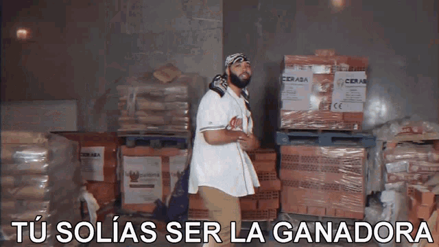 a man standing in a warehouse with the words tu solias ser la ganadora written below him