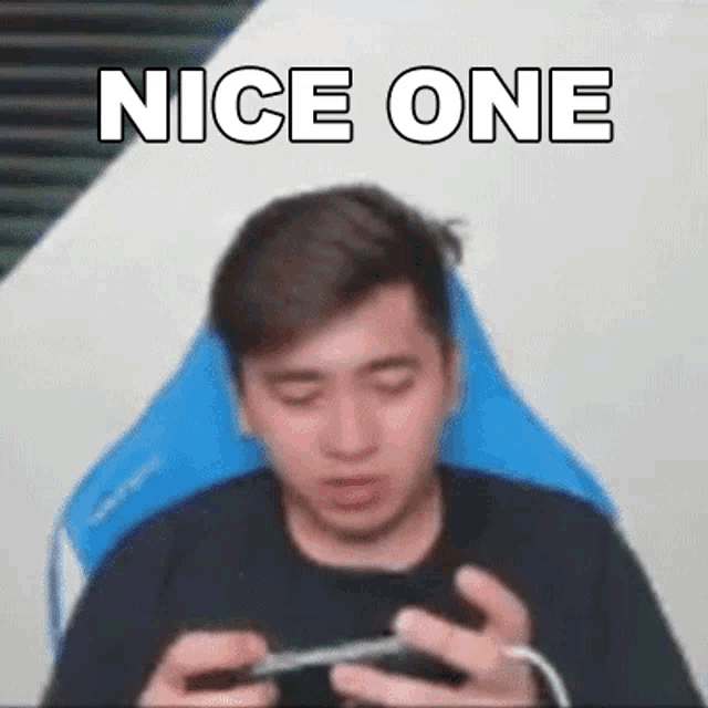 a man is sitting in a chair playing a video game with his eyes closed while holding a cell phone .