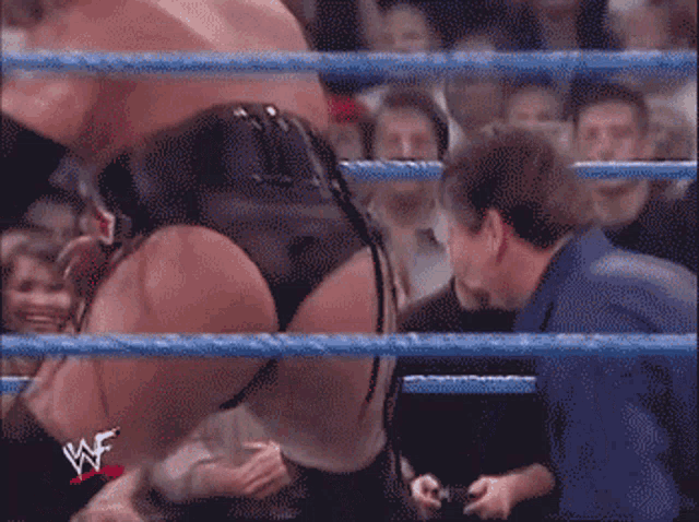 a man in a blue shirt stands in a wrestling ring with the letters wf on it