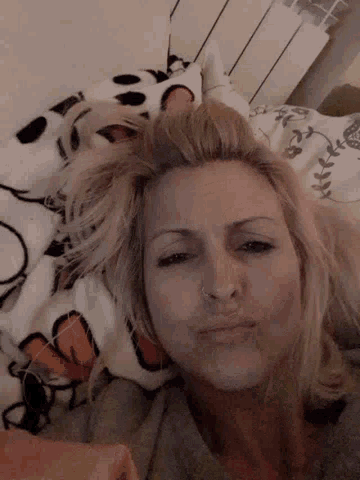 a woman with a nose ring is laying on a bed with a blanket on her head .