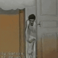 a man in a white suit is standing in front of a door