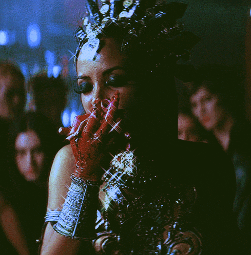 a woman with a crown on her head is holding her hand to her face