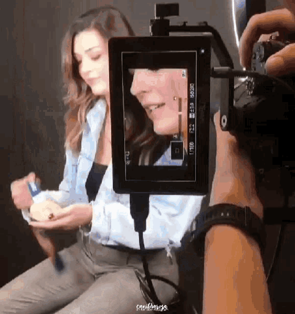 a person is taking a picture of a woman in front of a camera that says ' crew ' on the bottom left