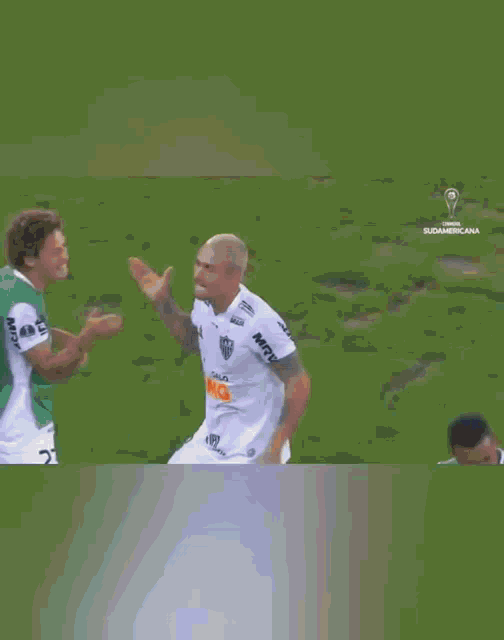 two soccer players are running on a field in front of a banner that says 1xe