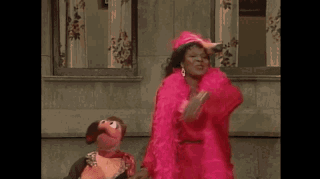 a couple of sesame street characters are standing next to each other in front of a building .