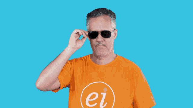 a man with a beard is wearing sunglasses and looking over his glasses