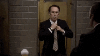 a man in a suit and tie is adjusting his tie in front of a mirror .