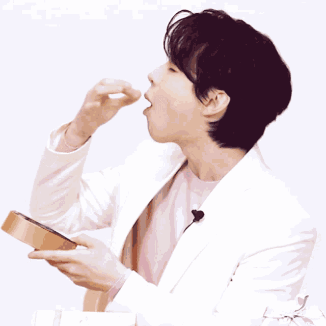a man wearing a pink shirt and a white jacket is eating something
