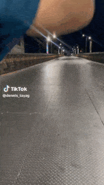 a person is walking across a bridge at night with a tiktok watermark on the bottom of the screen