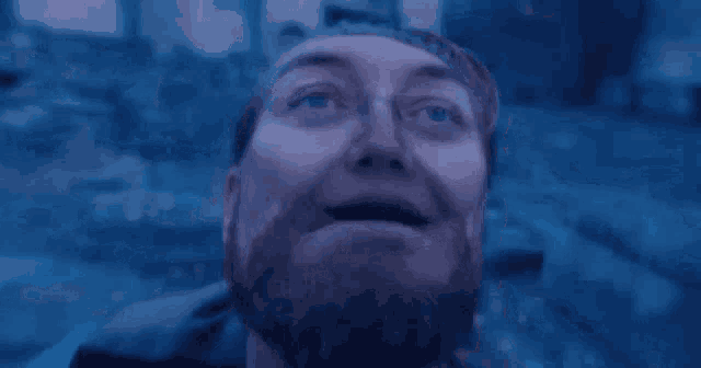 a close up of a man with a beard looking up at the sky .