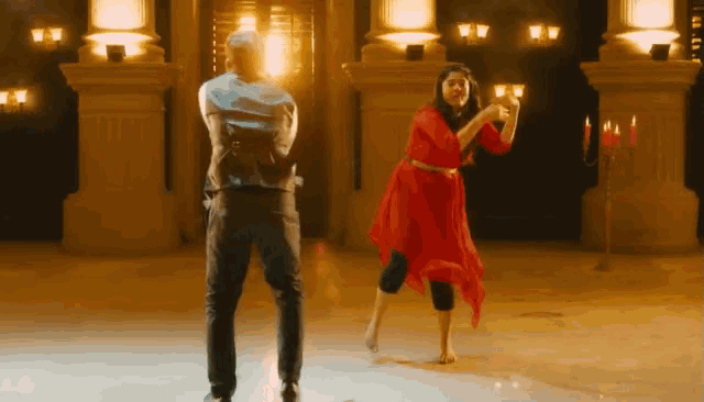 a woman in a red dress is dancing in front of a man