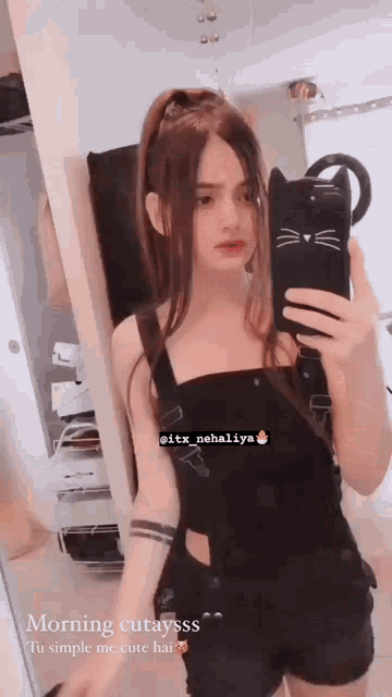 a girl is taking a selfie in front of a mirror with a cat case on her phone .