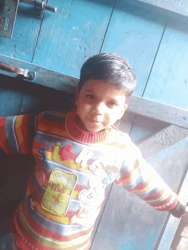a young boy wearing a colorful sweater with the letters a and g on it