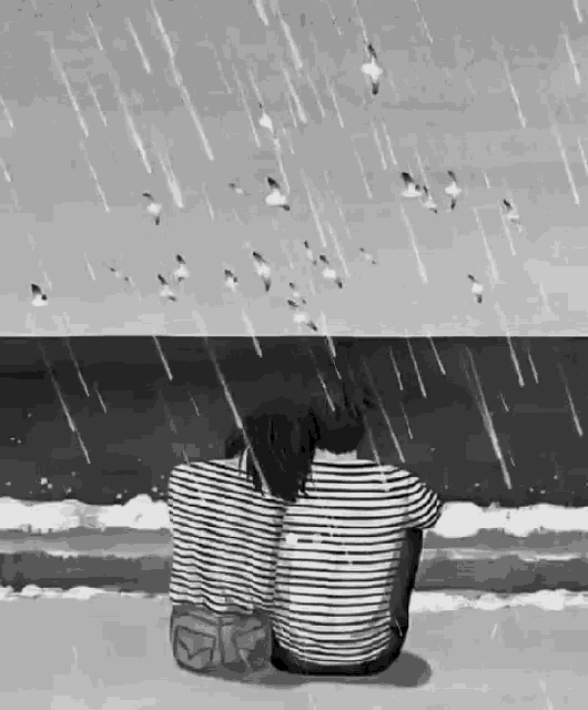a black and white drawing of a man and woman sitting on a beach in the rain .