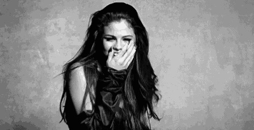 it is a black and white photo of a woman covering her mouth with her hand .