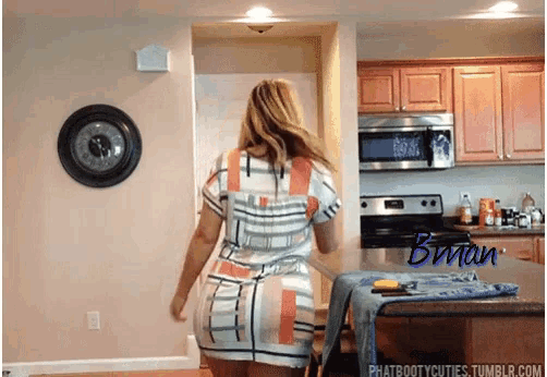 a woman in a plaid dress is dancing in a kitchen with the name brian on the bottom right