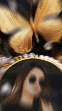 a blurry picture of a woman in a black hat with a butterfly on her head