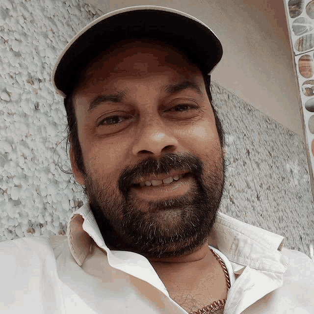 a man with a beard wearing a white shirt and a black hat
