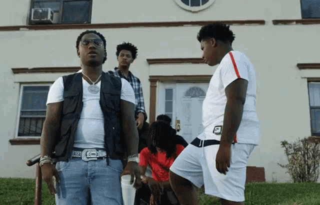 a group of young men standing in front of a white building one of them is wearing a white shirt that says nike on it