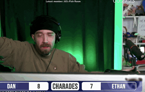 a man wearing headphones sits in front of a computer screen with the numbers 8 and 7 next to him