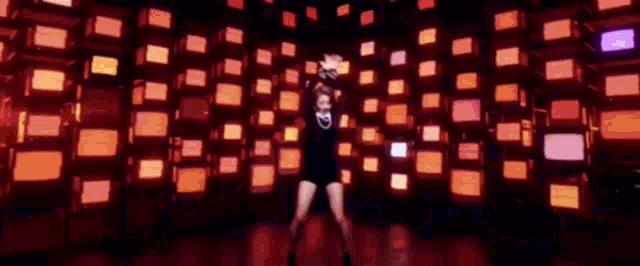 a woman is dancing in front of a wall of televisions .