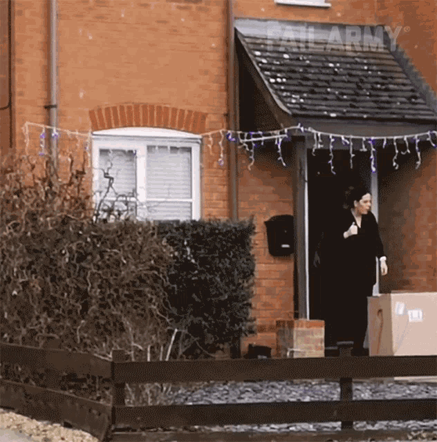 a woman stands in front of a brick house with a sign that says " fail army "
