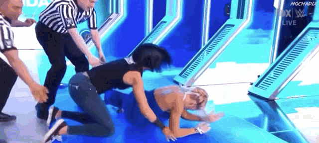 a woman is kneeling on the floor while a referee looks on