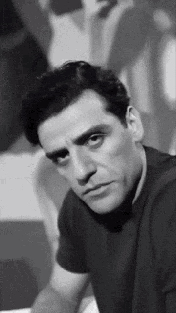 a black and white photo of a man looking at the camera .