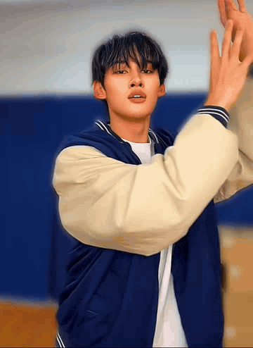 a young man in a blue and white baseball jacket is dancing .