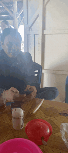 a man sits at a table looking at a cell phone
