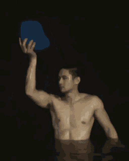 a shirtless man is holding a blue bucket over his head while standing in the water .