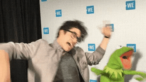 a man and kermit the frog are dancing in front of a wall that says we .