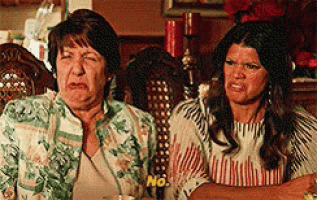 two women are sitting next to each other and one of them is making a face .