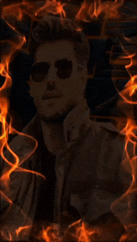 a man wearing sunglasses and a leather jacket is surrounded by flames