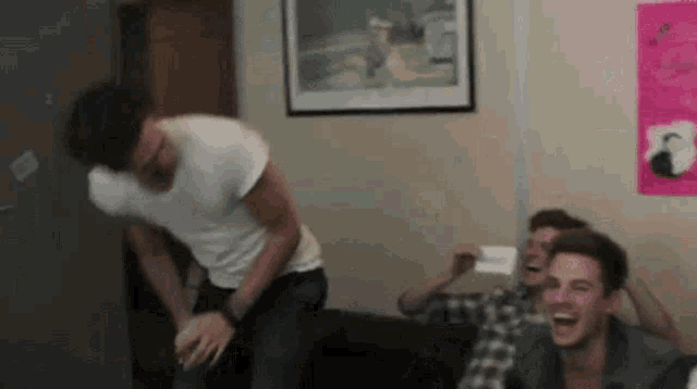 a group of young men are sitting in a living room laughing .