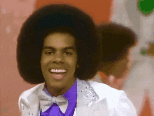 a man wearing a purple shirt and bow tie smiles