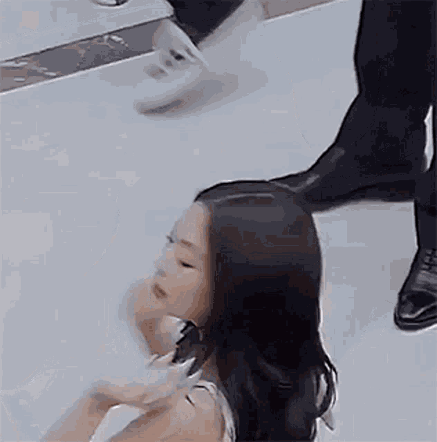 a woman is sitting on the floor holding a cup of coffee while a man walks past her .